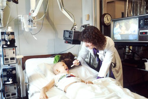 A doctor examines a pediatric patient who is receiving chemotherapy.