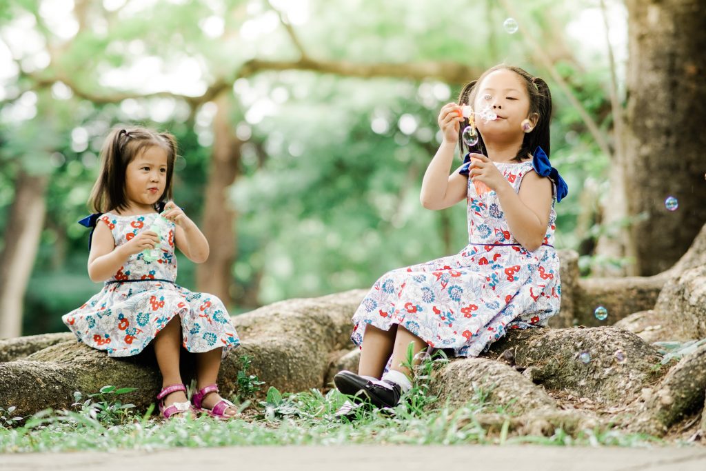 Girls in floral dresses playing bubbles